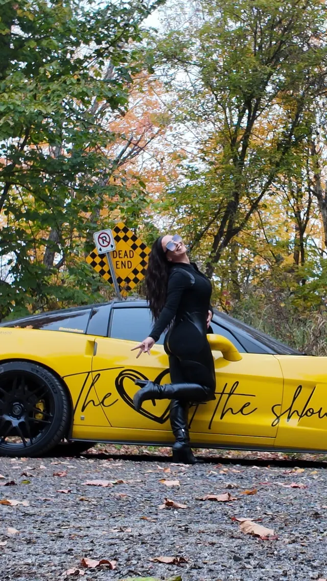 Chelsea mid-kick beside the Corvette and a Dead End sign.