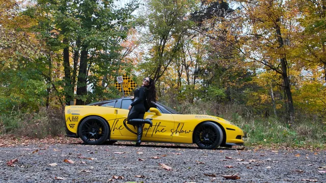 Chelsea leaning playfully on the side of the Corvette.